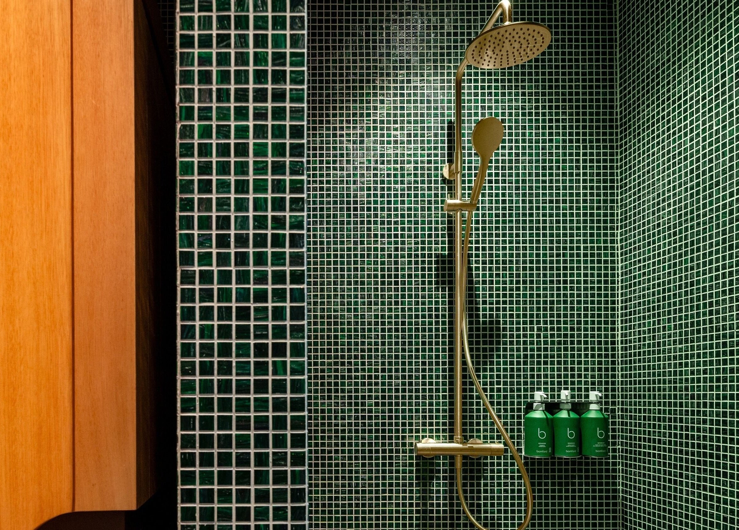 Elegant shower area at Lost/Found Spa, Hong Kong Island, HK, with green tiles and sleek bottles.
