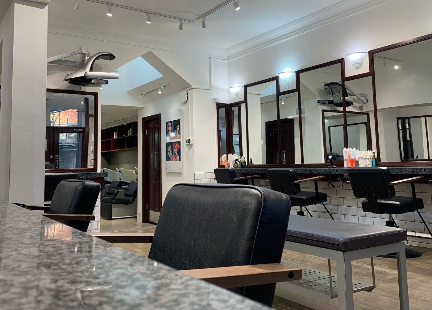 Modern salon interior at Mahogany Hair - Turl Street in Oxford, England, GB with stylish chairs and mirrors.
