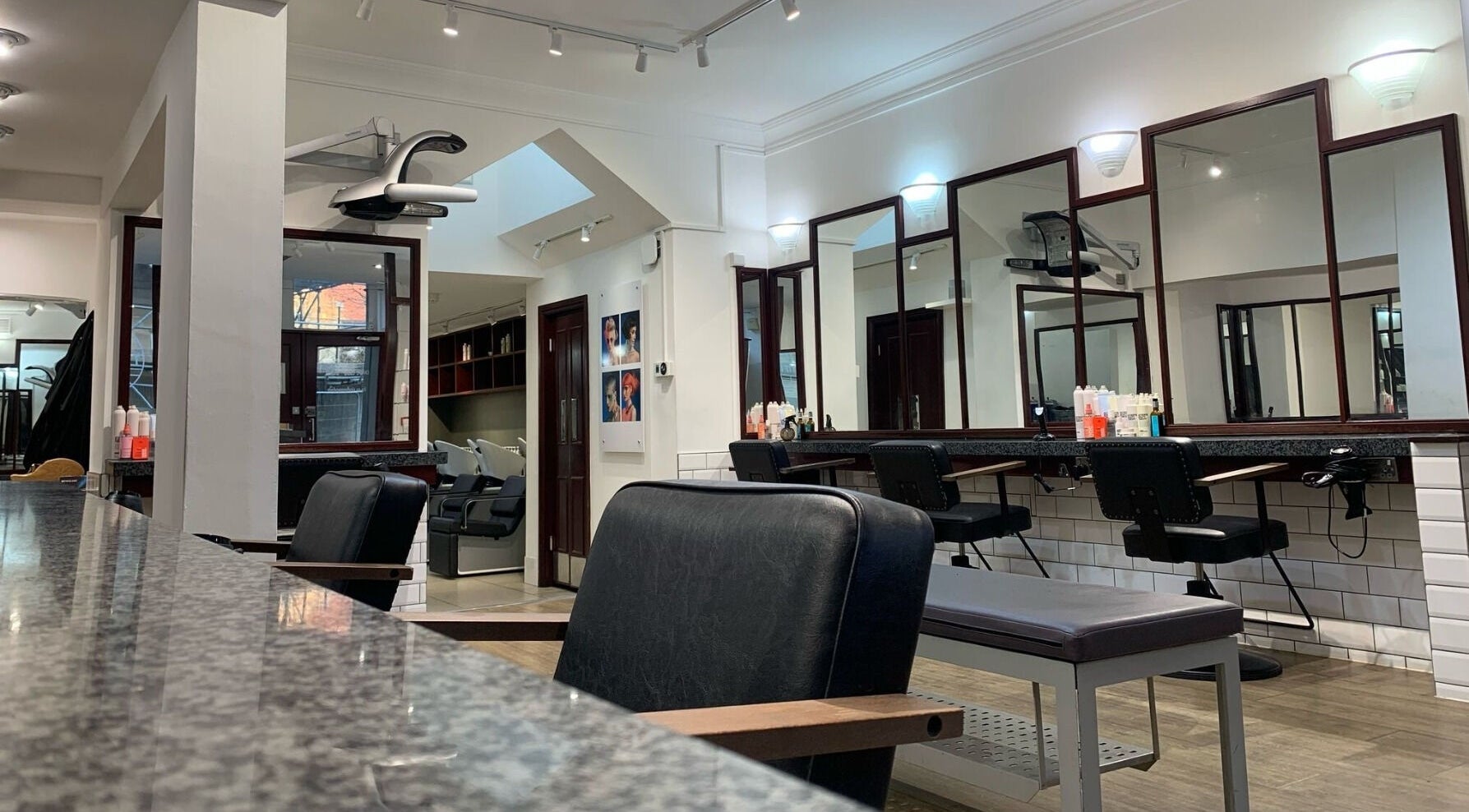 Modern salon interior at Mahogany Hair - Turl Street in Oxford, England, GB with stylish chairs and mirrors.