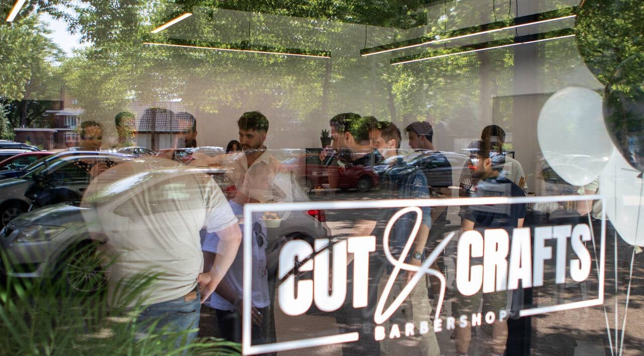 Cut & Crafts Barbershop bustling with activity at Eindhoven, Noord-brabant, NL through glass reflection.