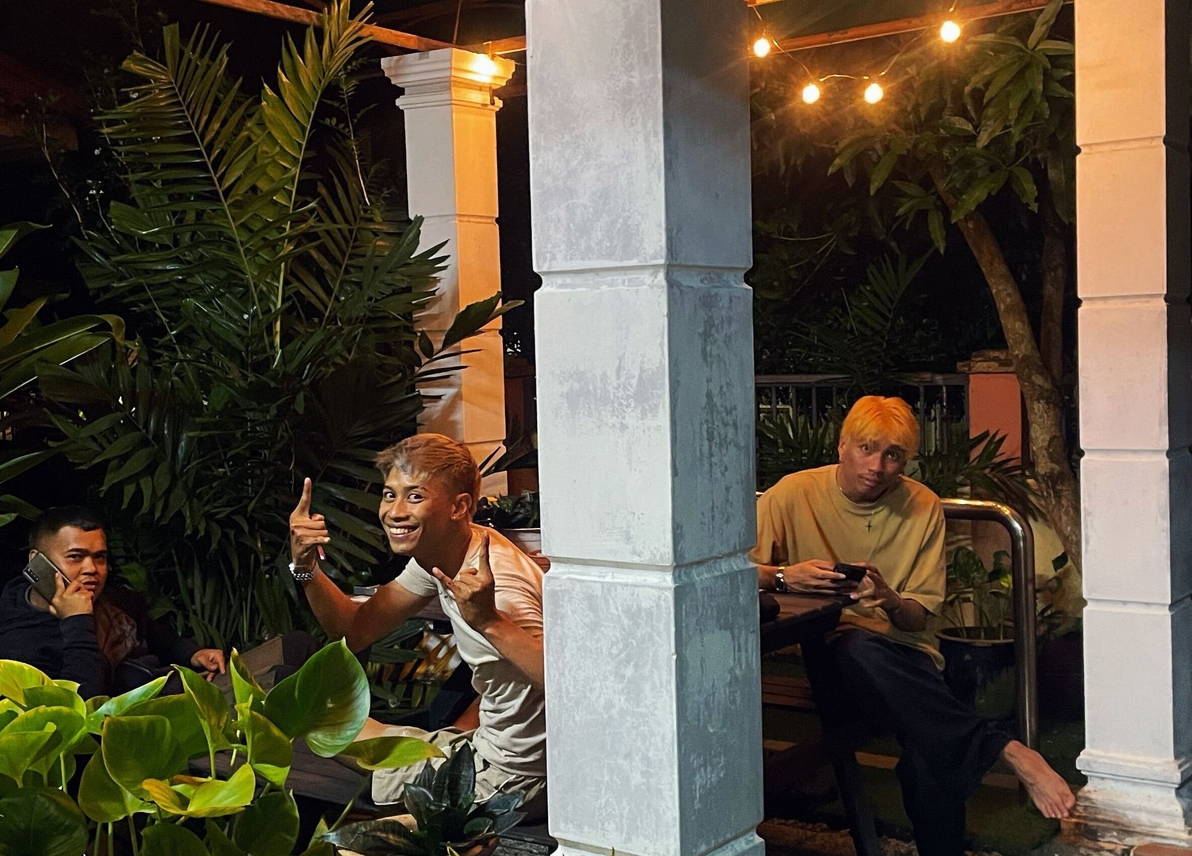 People relaxing on the outdoor patio at Room41 Barber, Klang, Selangor, MY, surrounded by lush greenery.