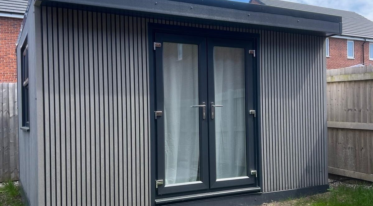 Modern cabin exterior at BelleVie Wellness, Liverpool, England, GB with sleek vertical paneling and glass doors.