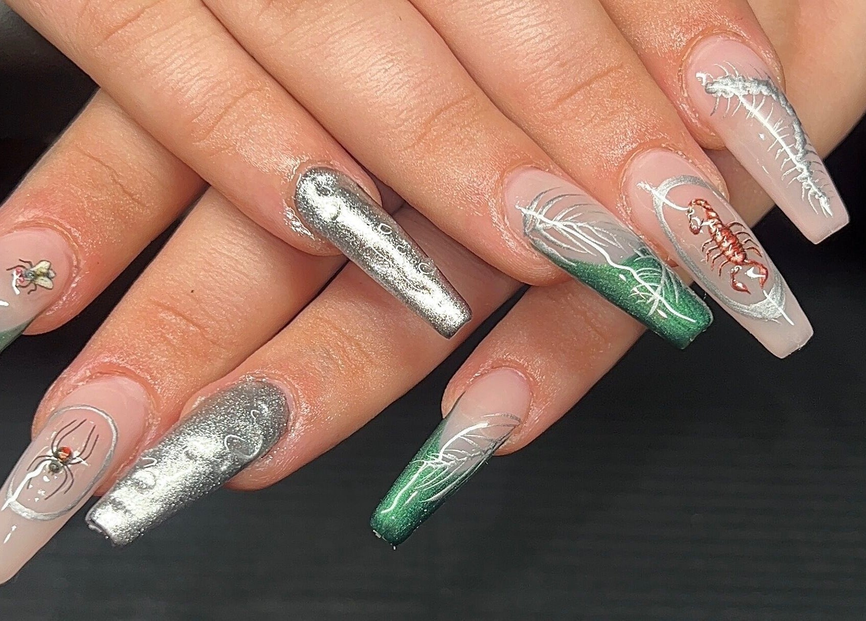 Artistic stiletto nails with green, silver designs at Nevar Beauty, Richlands, Queensland, AU.