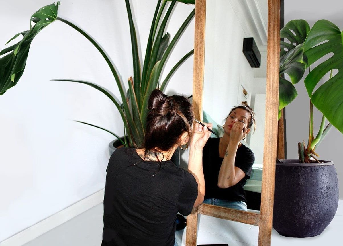 Vrouw maakt zich op voor een spiegel in Mariachi, Mechelen, Vlaams Gewest, BE, omgeven door groene planten.