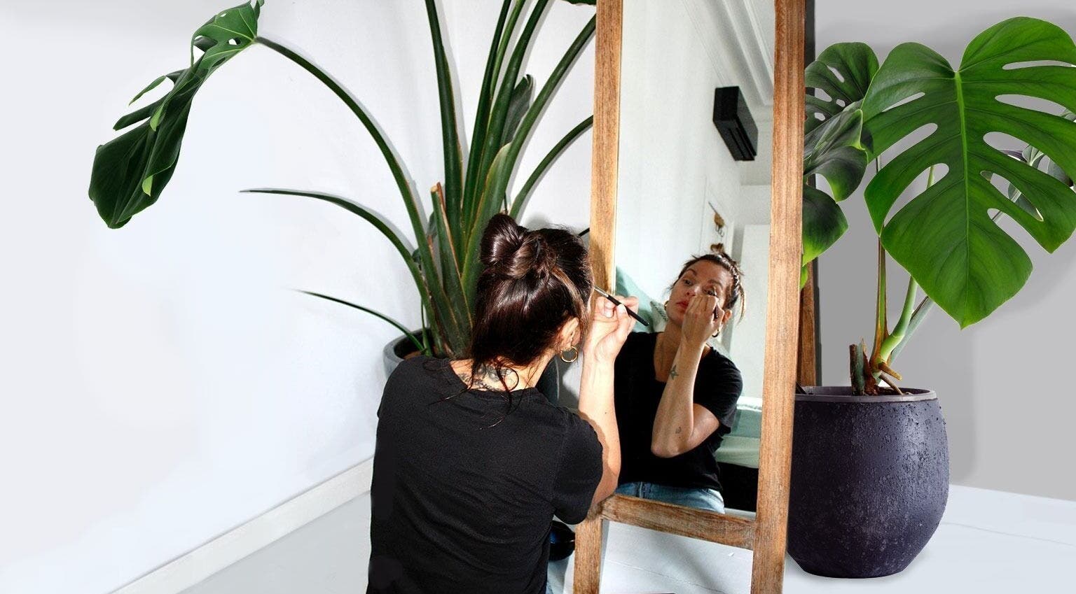 Vrouw maakt zich op voor een spiegel in Mariachi, Mechelen, Vlaams Gewest, BE, omgeven door groene planten.
