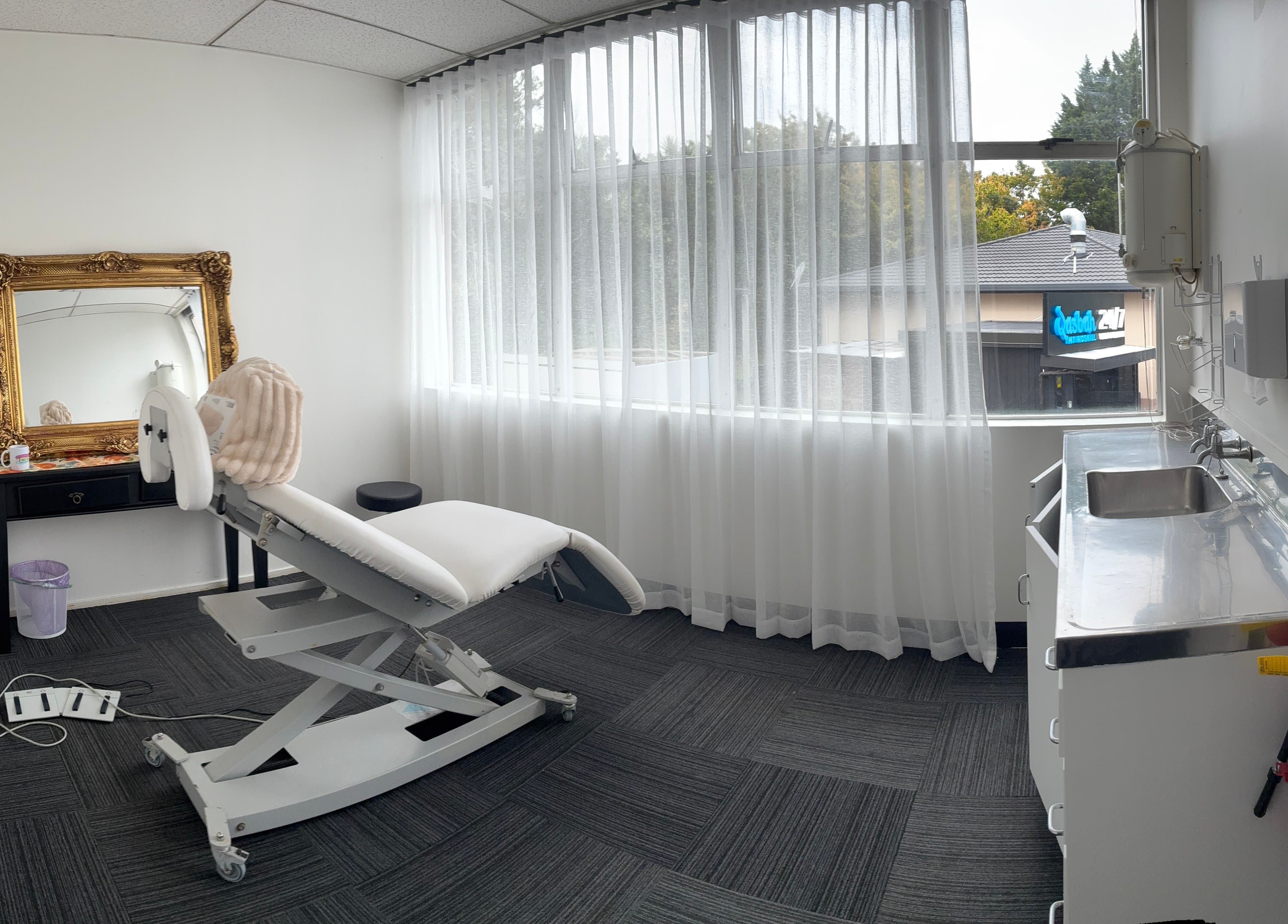 Comfortable treatment room at Viva Dentures, Auckland, NZ with a chair, mirror, and soft lighting.
