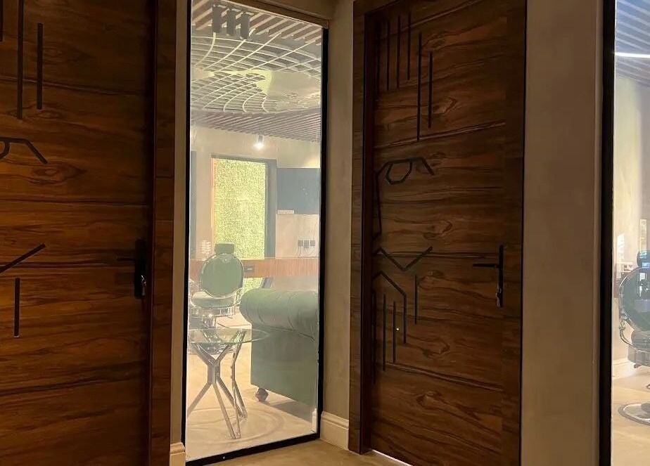 Stylish door design inside Scissor's Experts Salon, Riyadh, featuring modern barber chairs.
