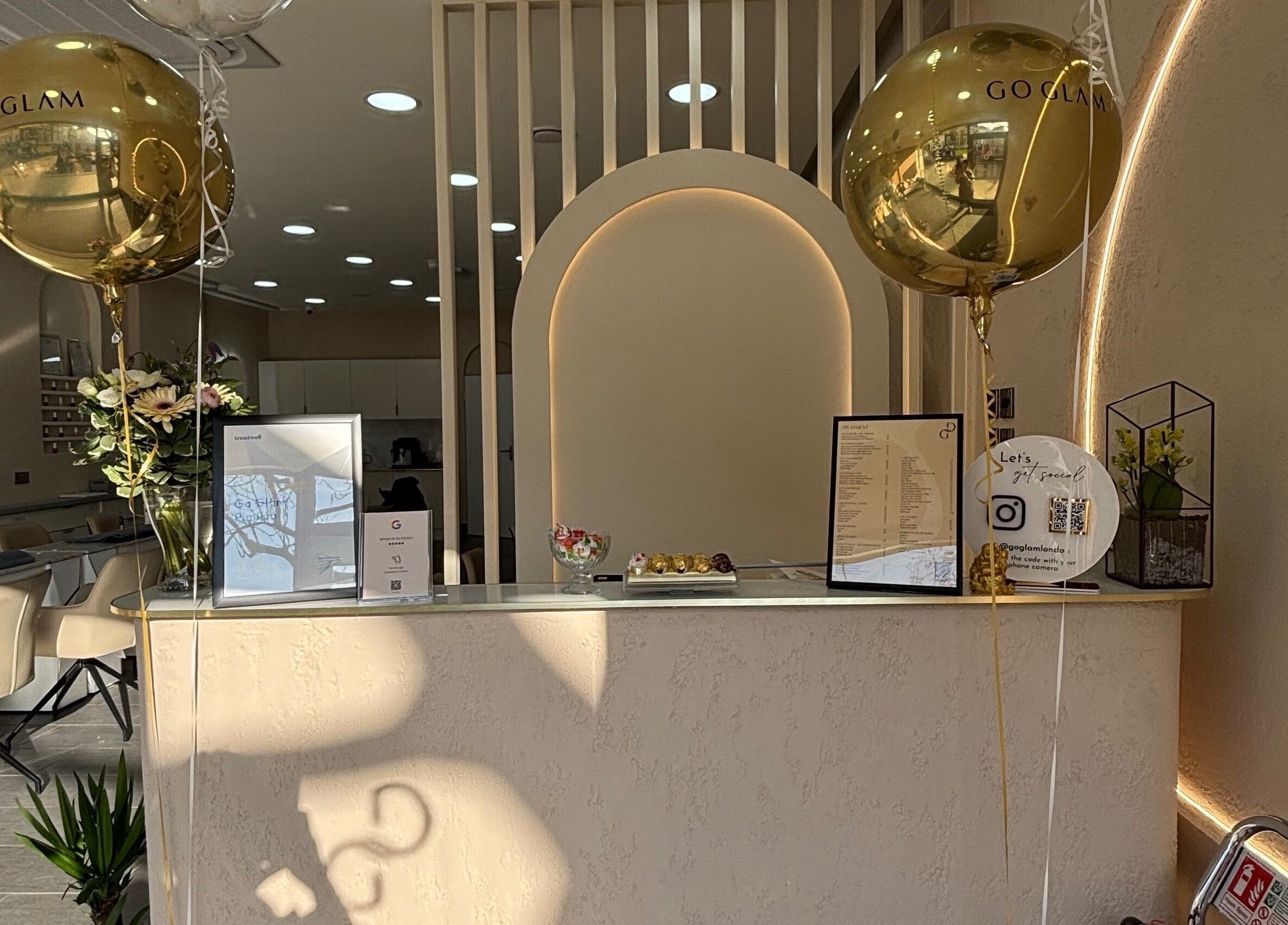 Chic reception area at Go Glam, London, England, GB featuring gold balloons and elegant decor.