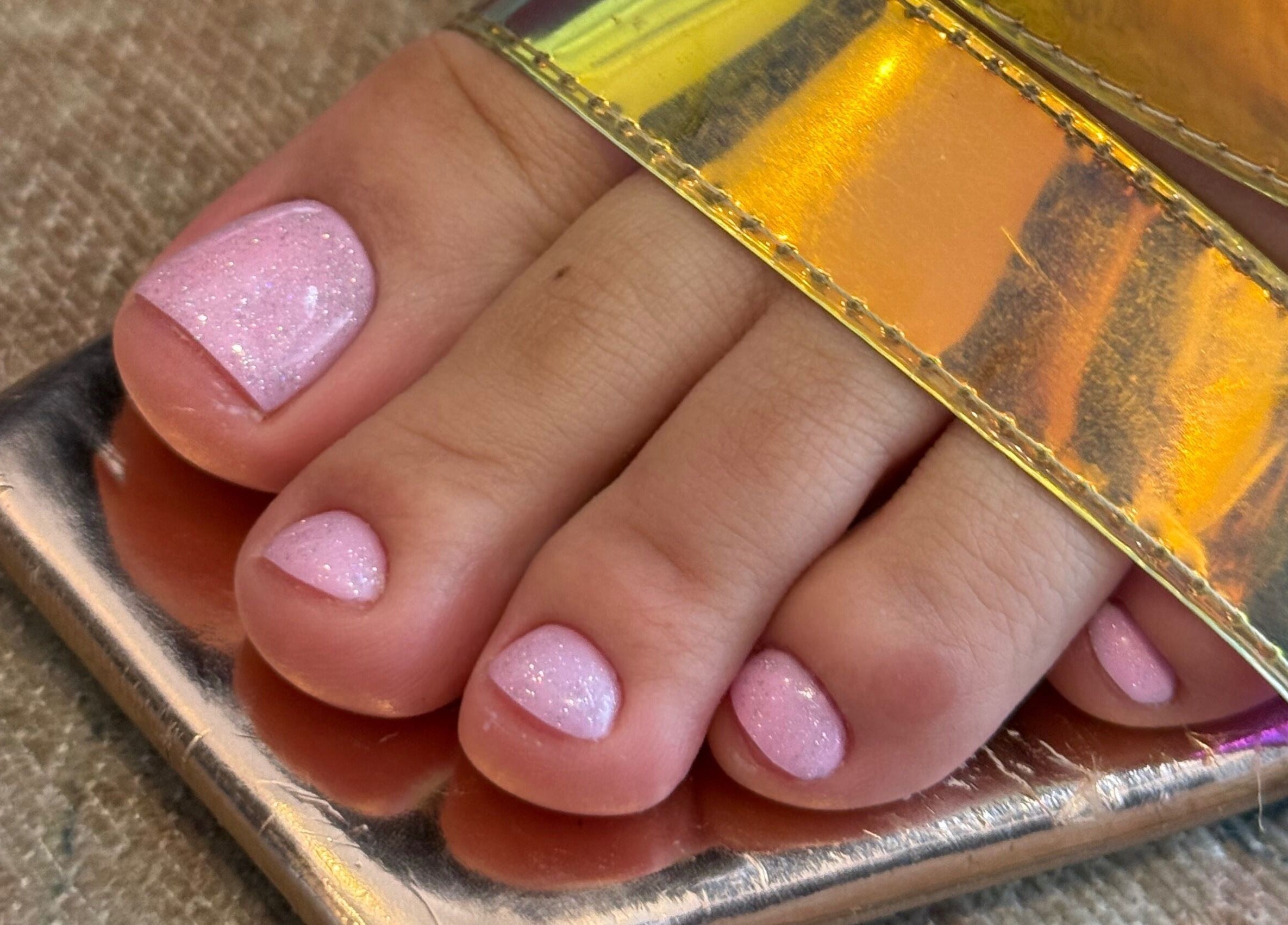 Pink glitter pedicure at Nailful Salon, Jeddah, Makkah Province, SA, showcasing nail care and style excellence.