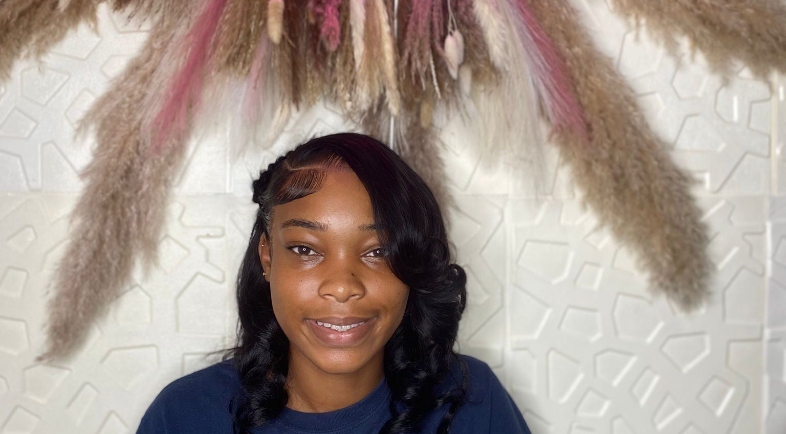 Smiling woman with styled hair at Styles By Kera, Roseau, Saint George Parish, DM, under decorative display.