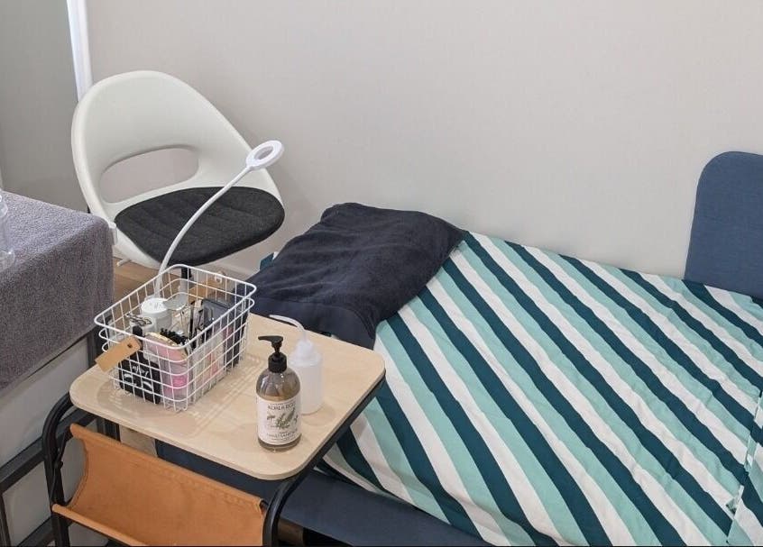 Cozy treatment space at Tokyo Eyelash in Kilburn, South Australia, with a striped bedspread and equipment.
