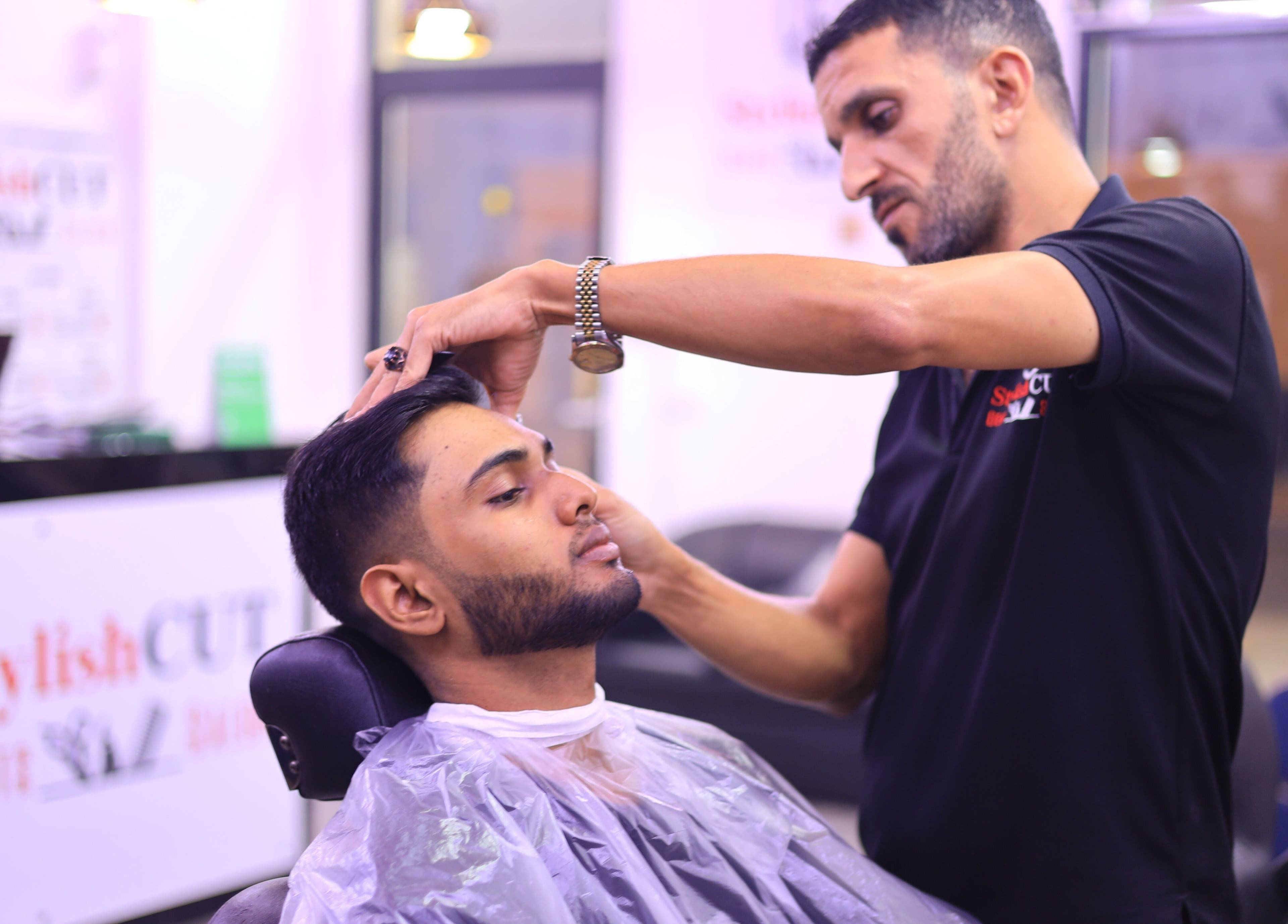 Professional barber styling hair at Stylish Cut Salon located in Sharjah, Sharjah, AE.