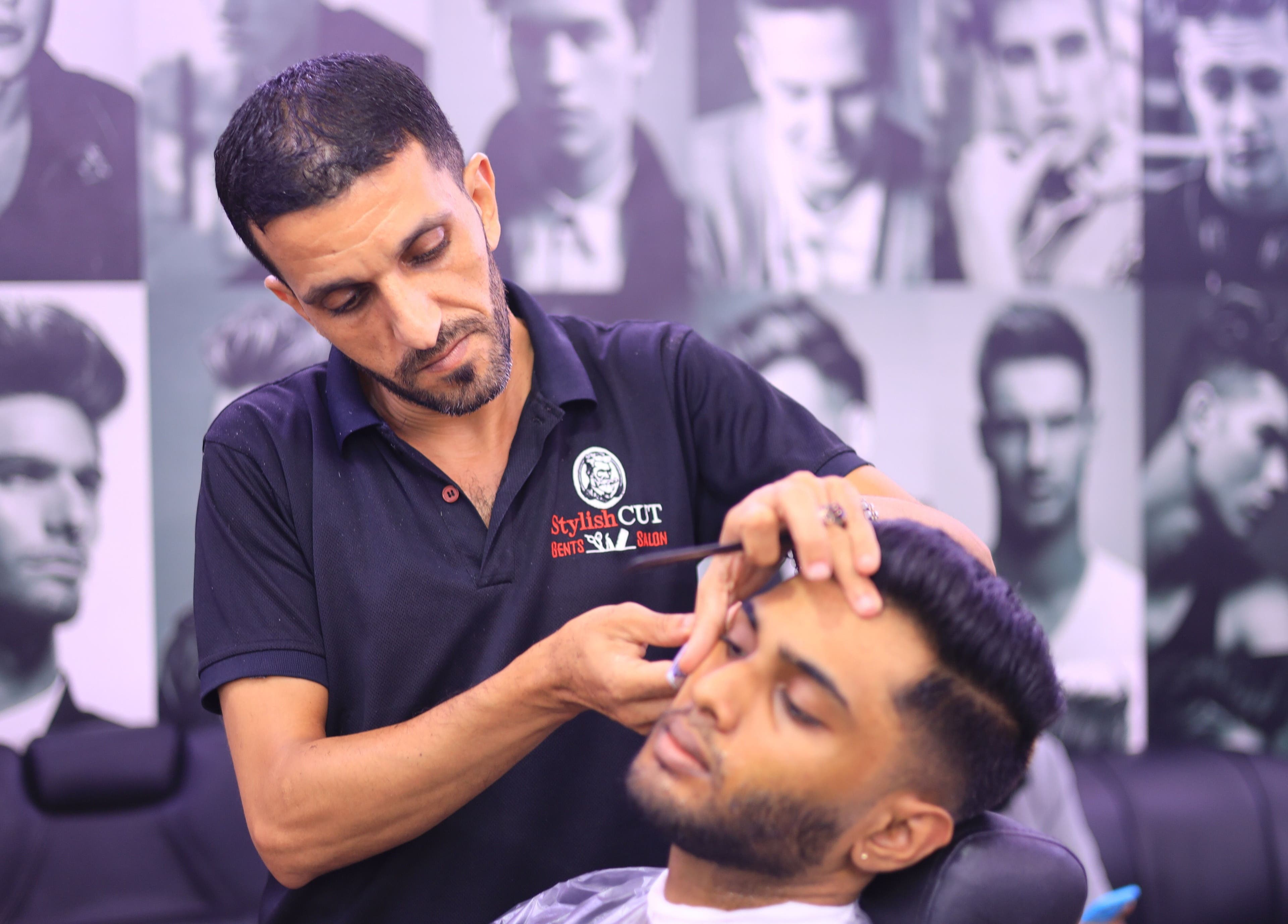 Barber at Stylish Cut Salon in Sharjah, AE expertly grooms a client.