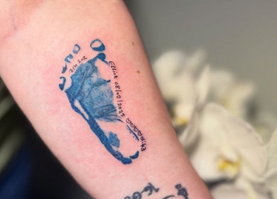 Personalized tattoo showcasing a baby's footprint at Hellhouse salon, Norwich, England, GB.
