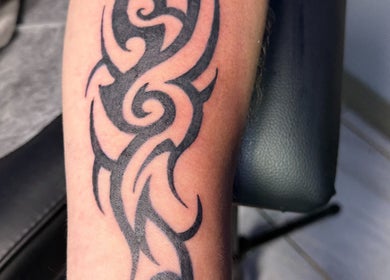 Tribal tattoo design on arm at Hellhouse salon, Norwich, England, GB showcasing fine ink artistry.