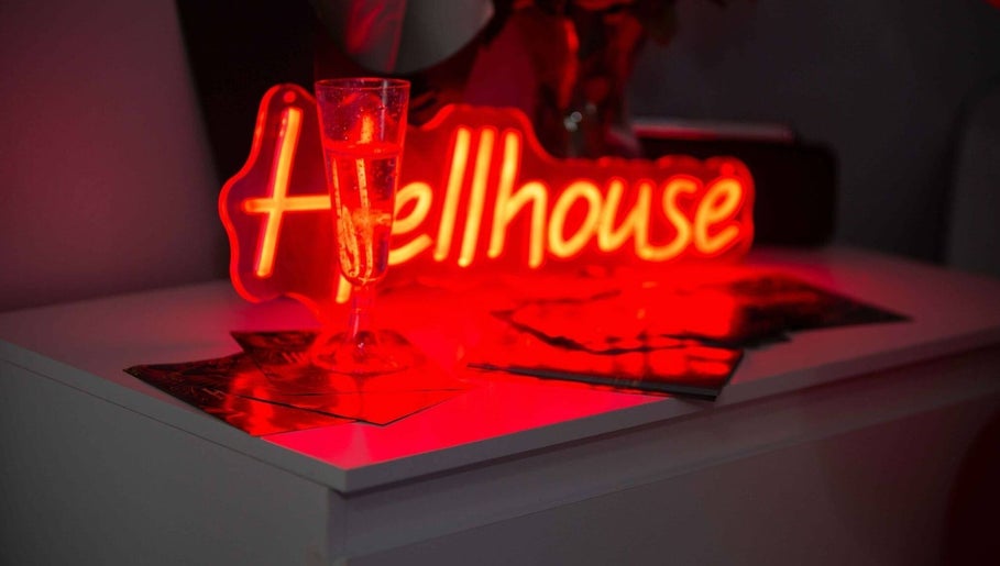 Chic neon sign with a glass at Hellhouse salon, Norwich, England, GB creating a modern relaxed setting.