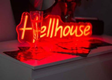 Chic neon sign with a glass at Hellhouse salon, Norwich, England, GB creating a modern relaxed setting.