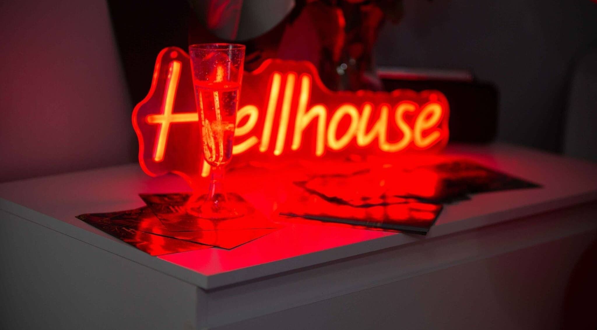 Chic neon sign with a glass at Hellhouse salon, Norwich, England, GB creating a modern relaxed setting.