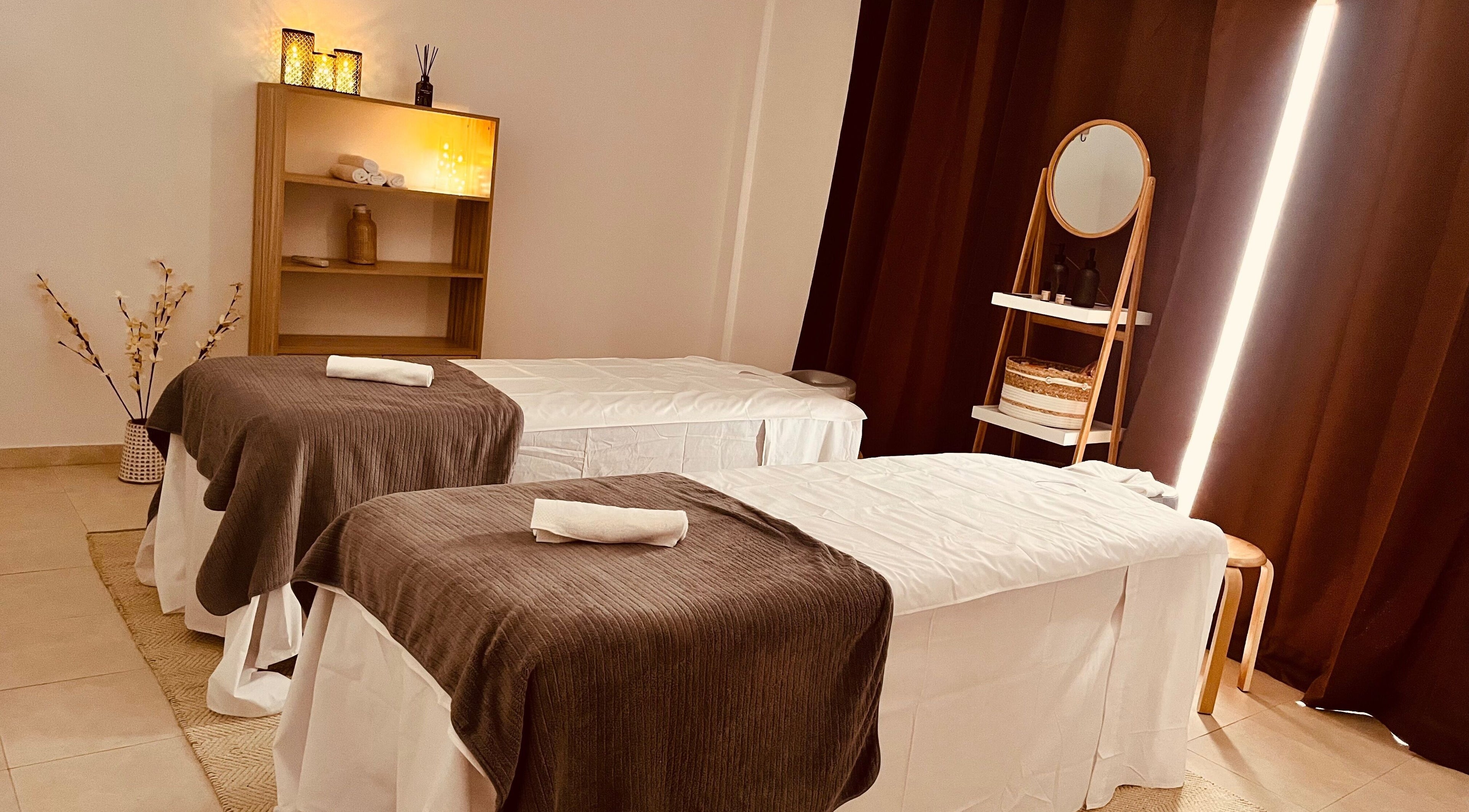 Sala de masajes en The Island Wellness, Port D'andratx, Illes Balears, ES, con camillas gemelas y decoración cálida.