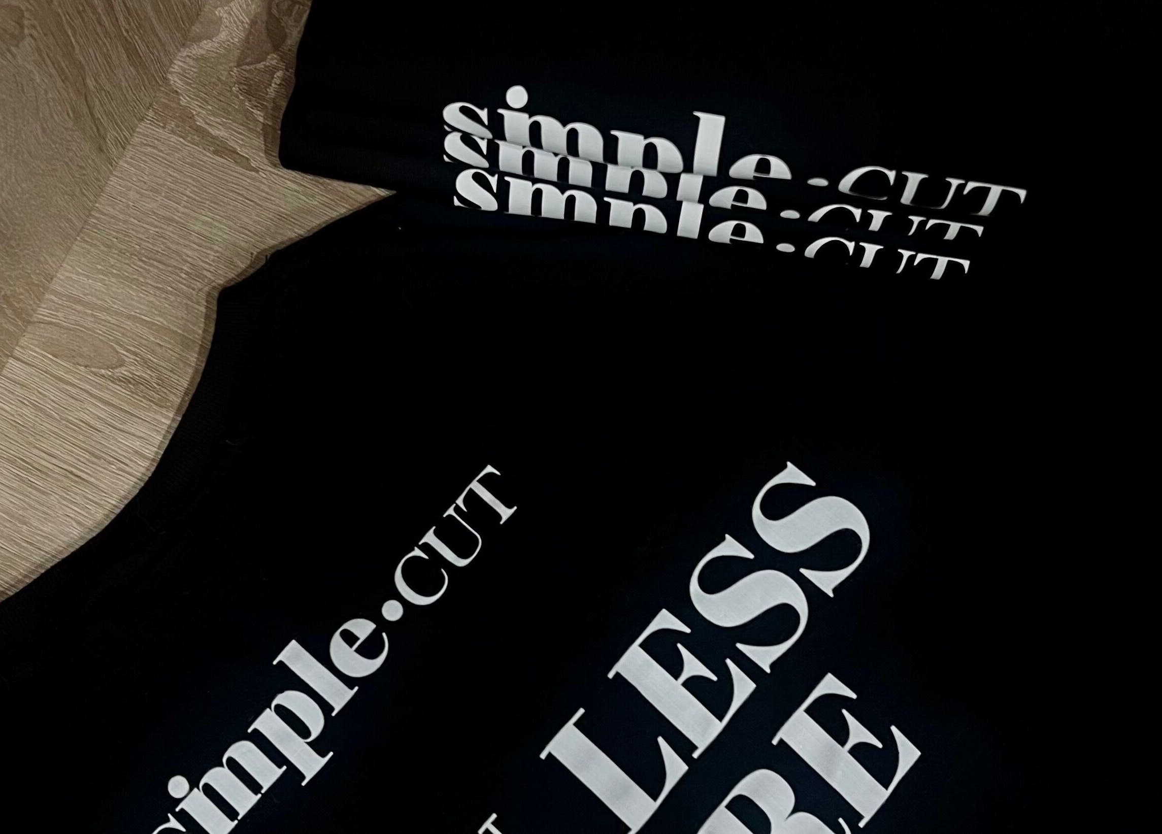 Simple Cut Budapest, Magyar, HU: Fekete pólók fehér logóval a földön.