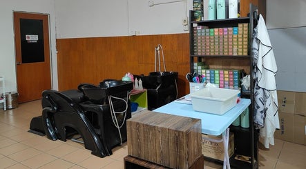 Modern wash area at 008 Hair & Beauty Studio, Ipoh, Perak, MY, showcasing sleek black chairs and vibrant products.