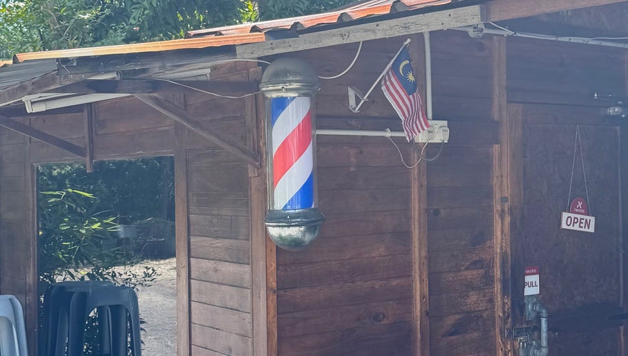 Barber pole at Aididthebarber, a rustic wooden venue in Klang, Selangor, MY, with a Malaysian flag and open sign.