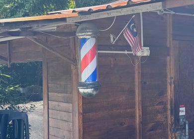 Classic barber pole at Aididthebarber, Klang, Selangor, MY, enhancing its rustic wooden exterior.