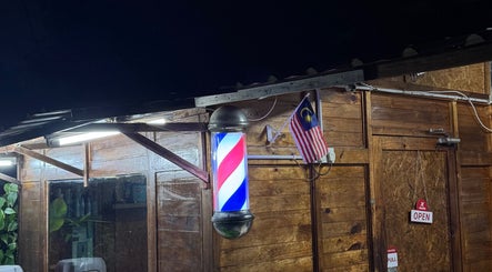Aididthebarber's rustic exterior with a glowing barber pole in Klang, Selangor, MY.