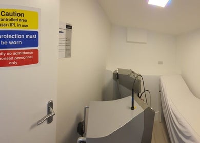 Treatment room at Citrine Clinic, Ilford, England, GB with laser equipment and safety signs.