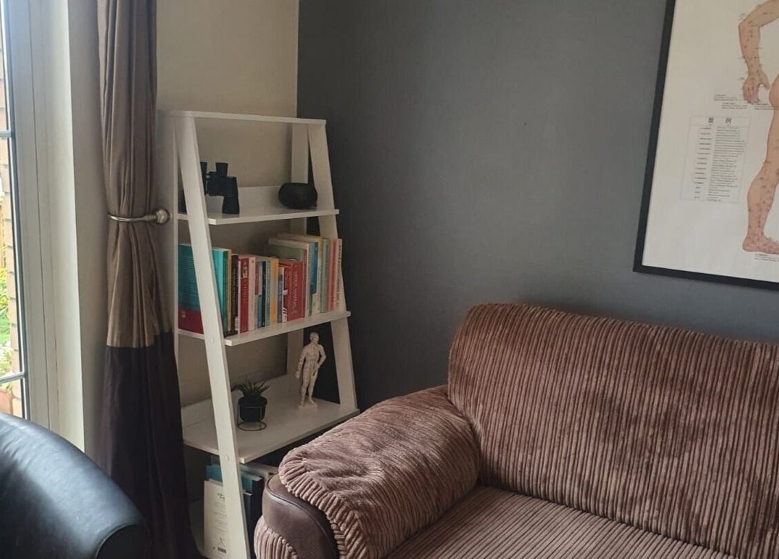 Cozy corner at Pure Acupuncture NI - The Tranquillity Room, Lisburn, featuring a plush sofa and bookshelf.