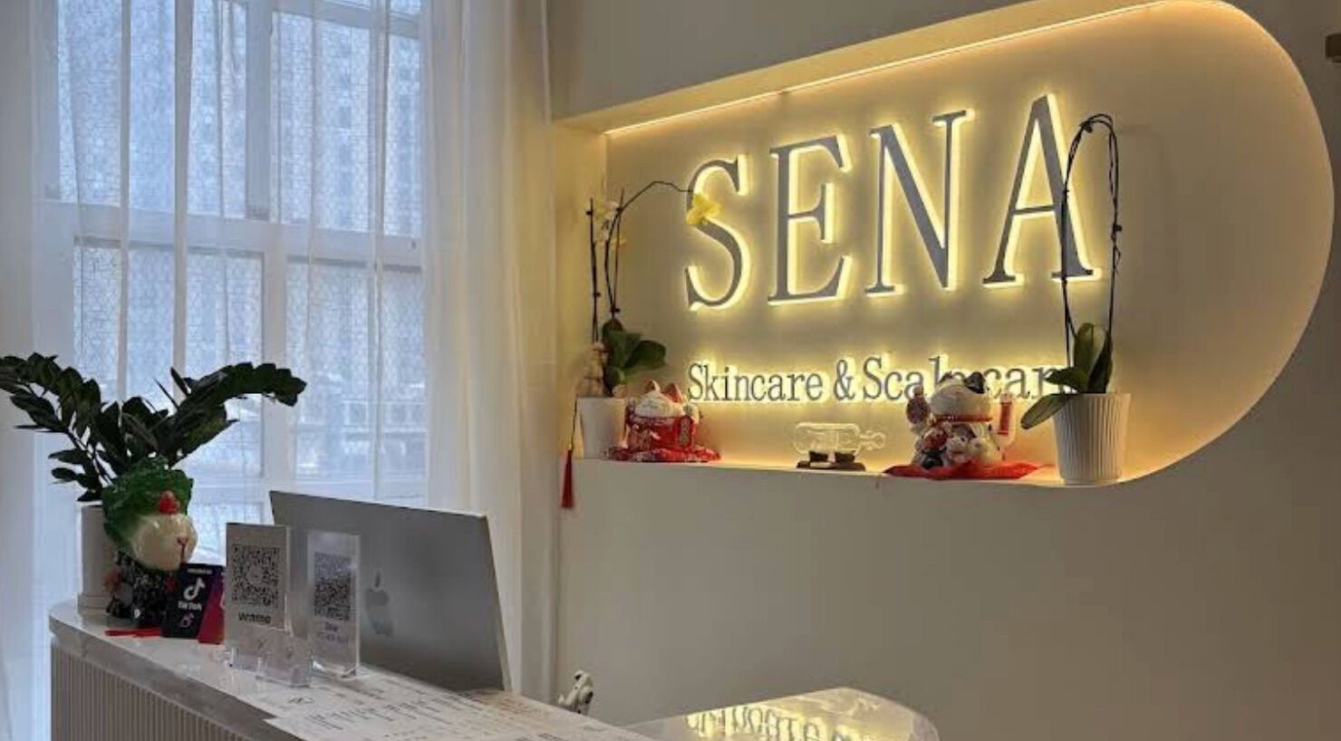 Reception area of SENA in New York, New York, US, featuring elegant decor and illuminated signage.