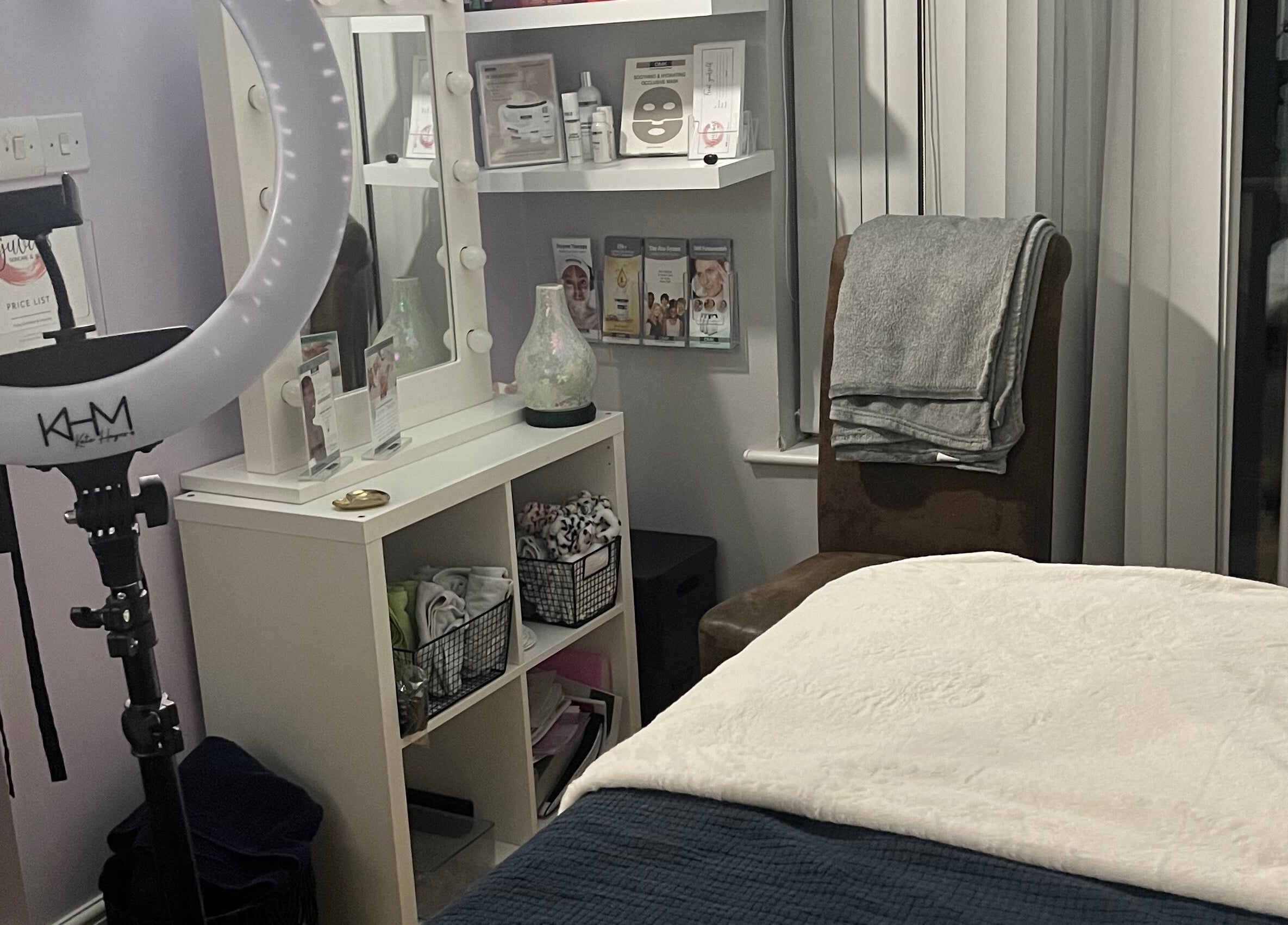Cozy treatment room at Rejuvin8, Slyne, England, GB, featuring a massage bed, ring light, and beauty products.