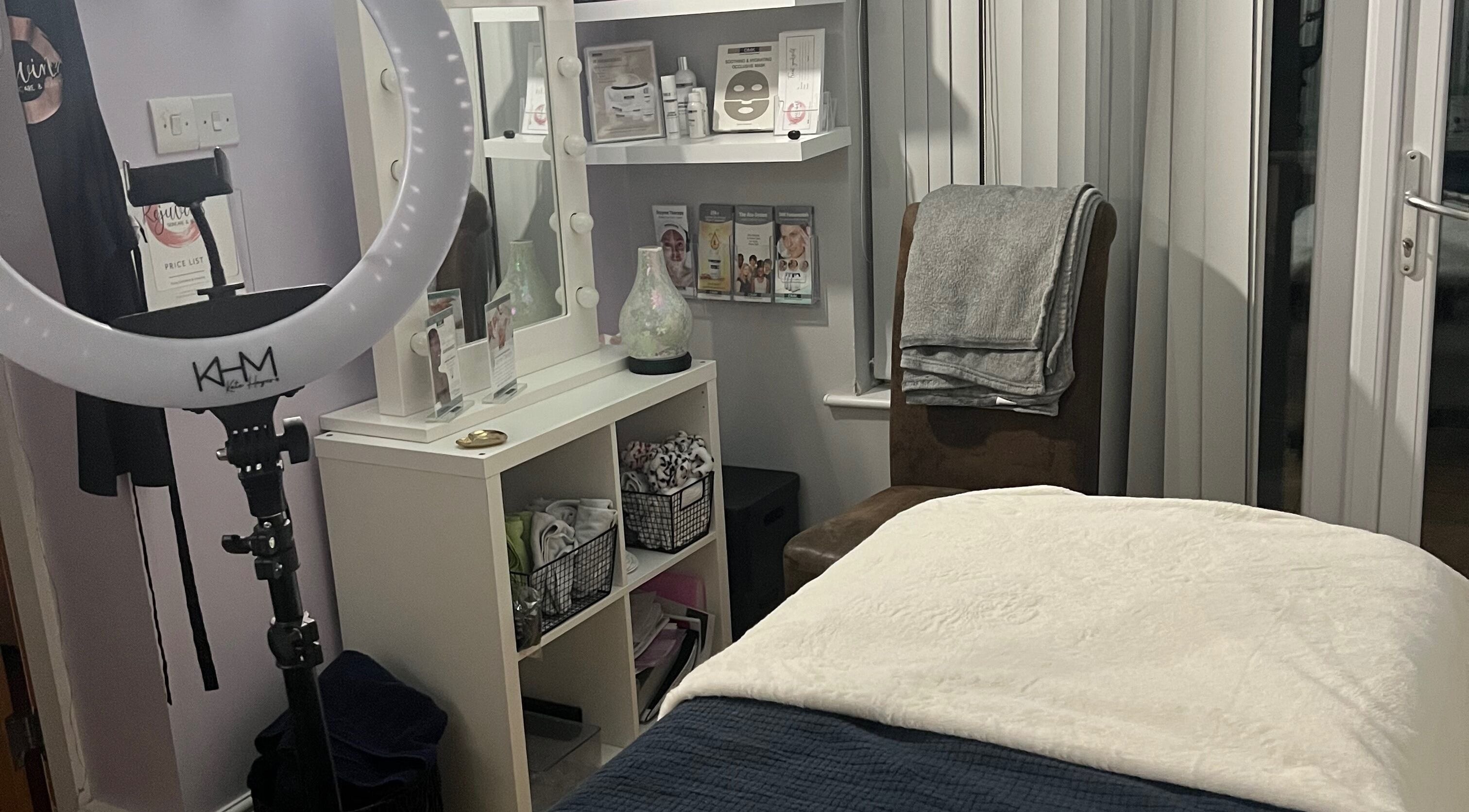 Cozy treatment room at Rejuvin8, Slyne, England, GB, featuring a massage bed, ring light, and beauty products.