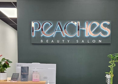 Reception at Peaches Beauty Salon in Timaru, Canterbury Region, NZ with glowing signage and plants.