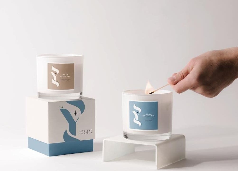 Hand lighting gourmet candle at SYS Beauty Lounge, Dubai, Dubai, AE for a serene ambiance.