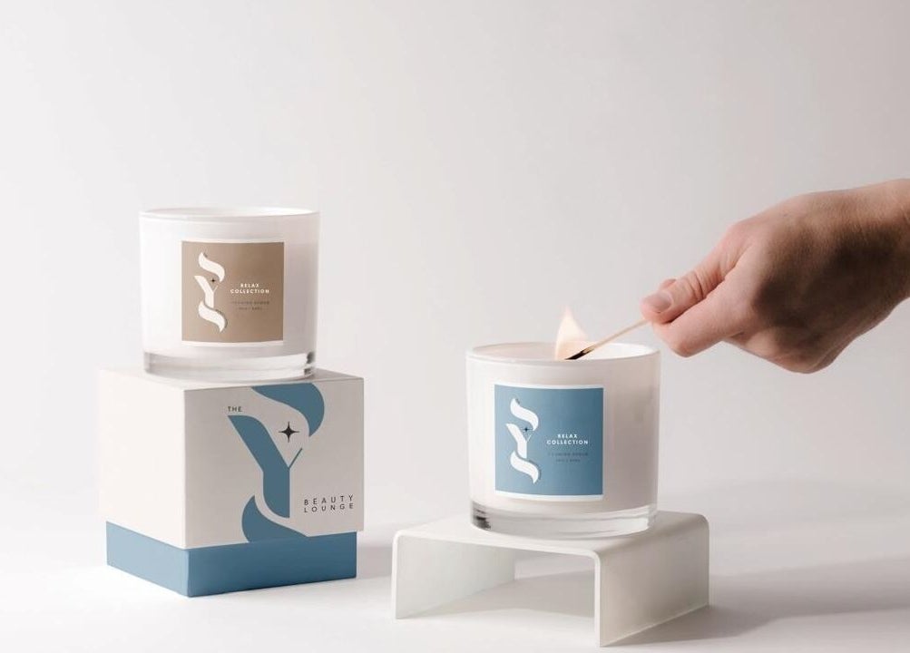 Hand lighting gourmet candle at SYS Beauty Lounge, Dubai, Dubai, AE for a serene ambiance.