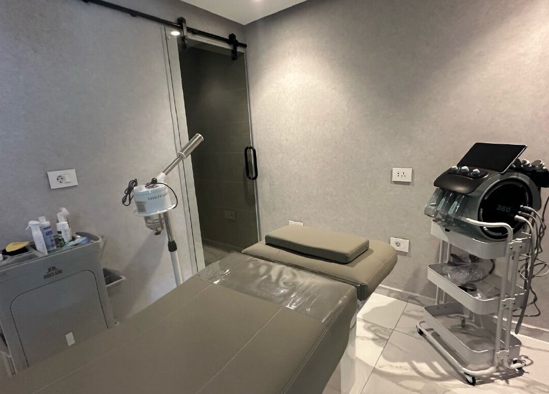 Convo's modern treatment room in Amman, Amman Governorate, JO featuring advanced equipment and a massage table.