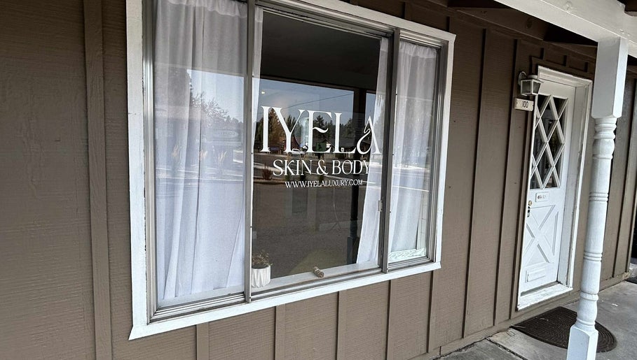 Shopfront window of Aesthetics by Juhliah J M in Bend, Oregon, US, reflecting a serene street view.