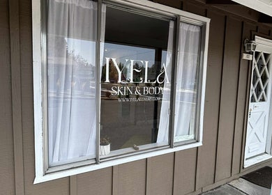 Shopfront window of Aesthetics by Juhliah J M in Bend, Oregon, US, reflecting a serene street view.