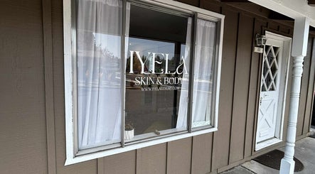 Shopfront window of Aesthetics by Juhliah J M in Bend, Oregon, US, reflecting a serene street view.