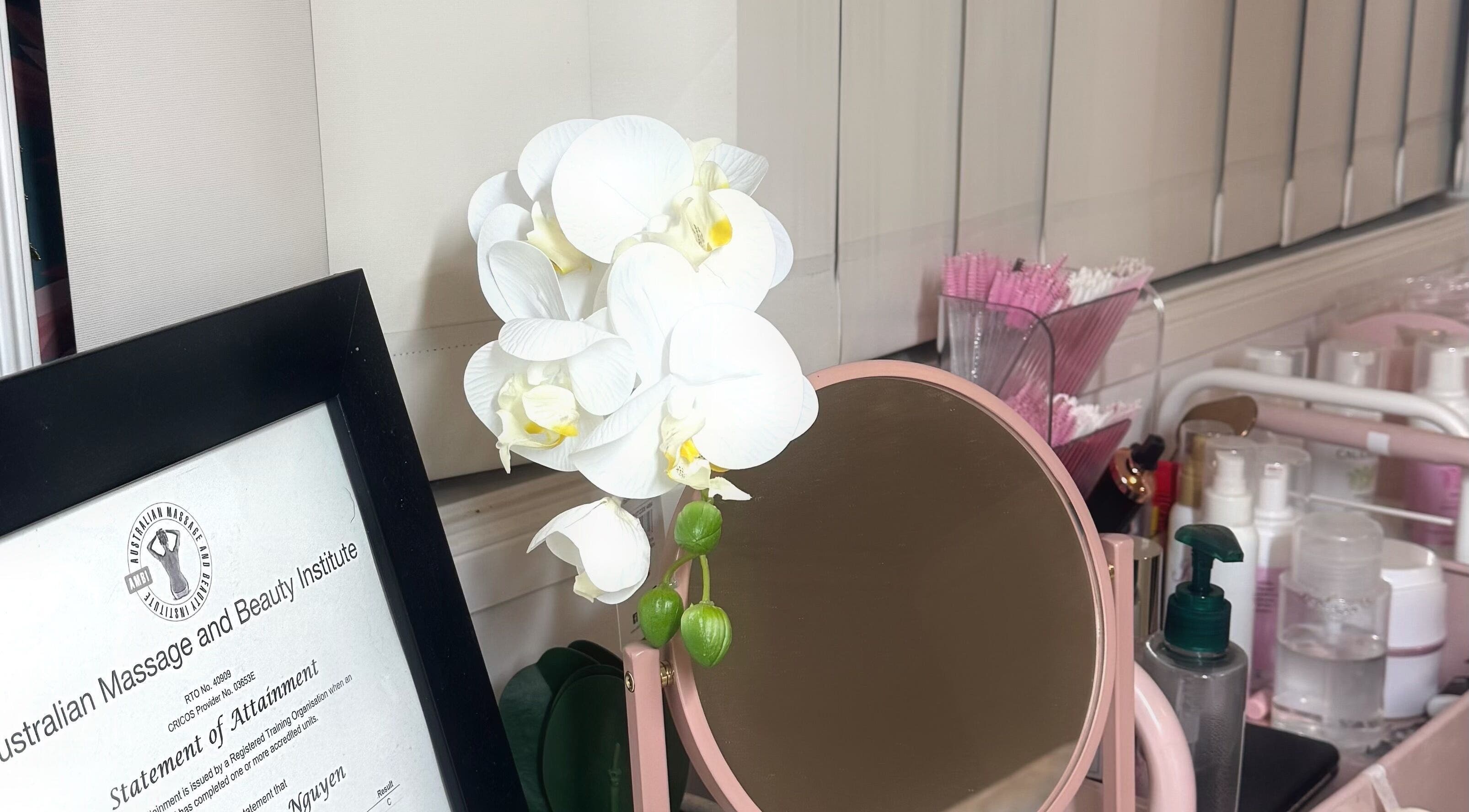 A serene beauty setup at V's Lashes, Hamlyn Terrace, New South Wales with orchid, mirror, and beauty products.