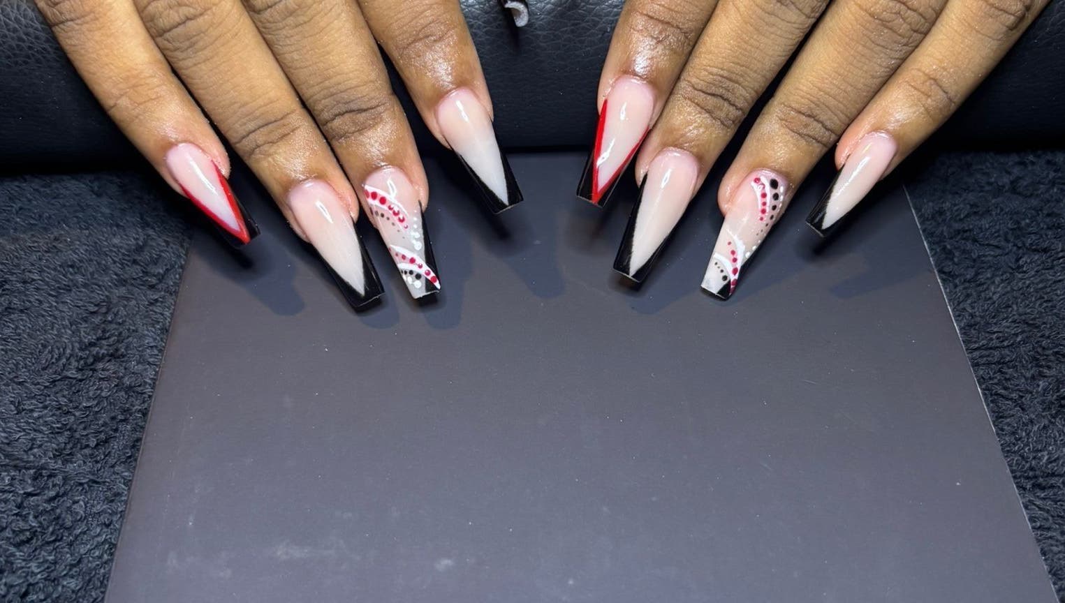 Elegant nail art with red and black designs at STUDIO 10, FREEPORT, Grand Bahama, BS.