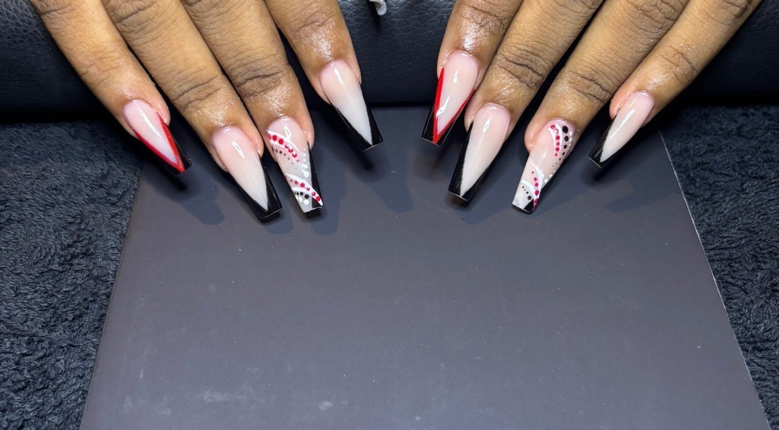 Elegant nail art with red and black designs at STUDIO 10, FREEPORT, Grand Bahama, BS.
