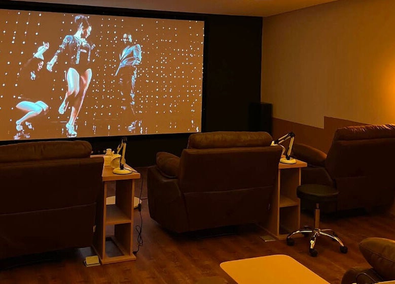 Luxurious recliners at Popcorn Nail Studio, Bali with a large screen for client relaxation.