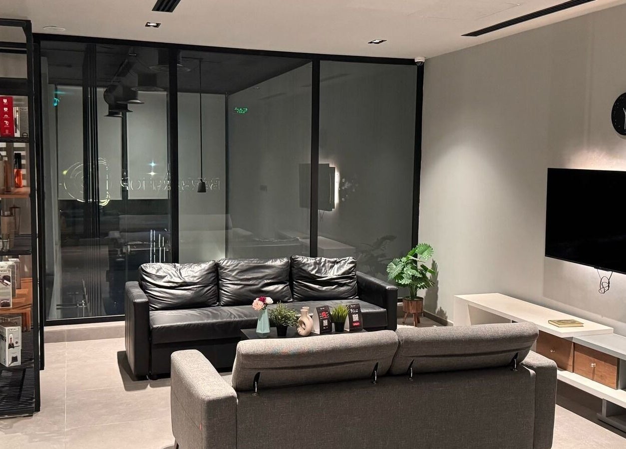 Sleek lounge area at D Van Barbershop, Riyadh, Riyadh Province, SA with black sofa and plant decor.