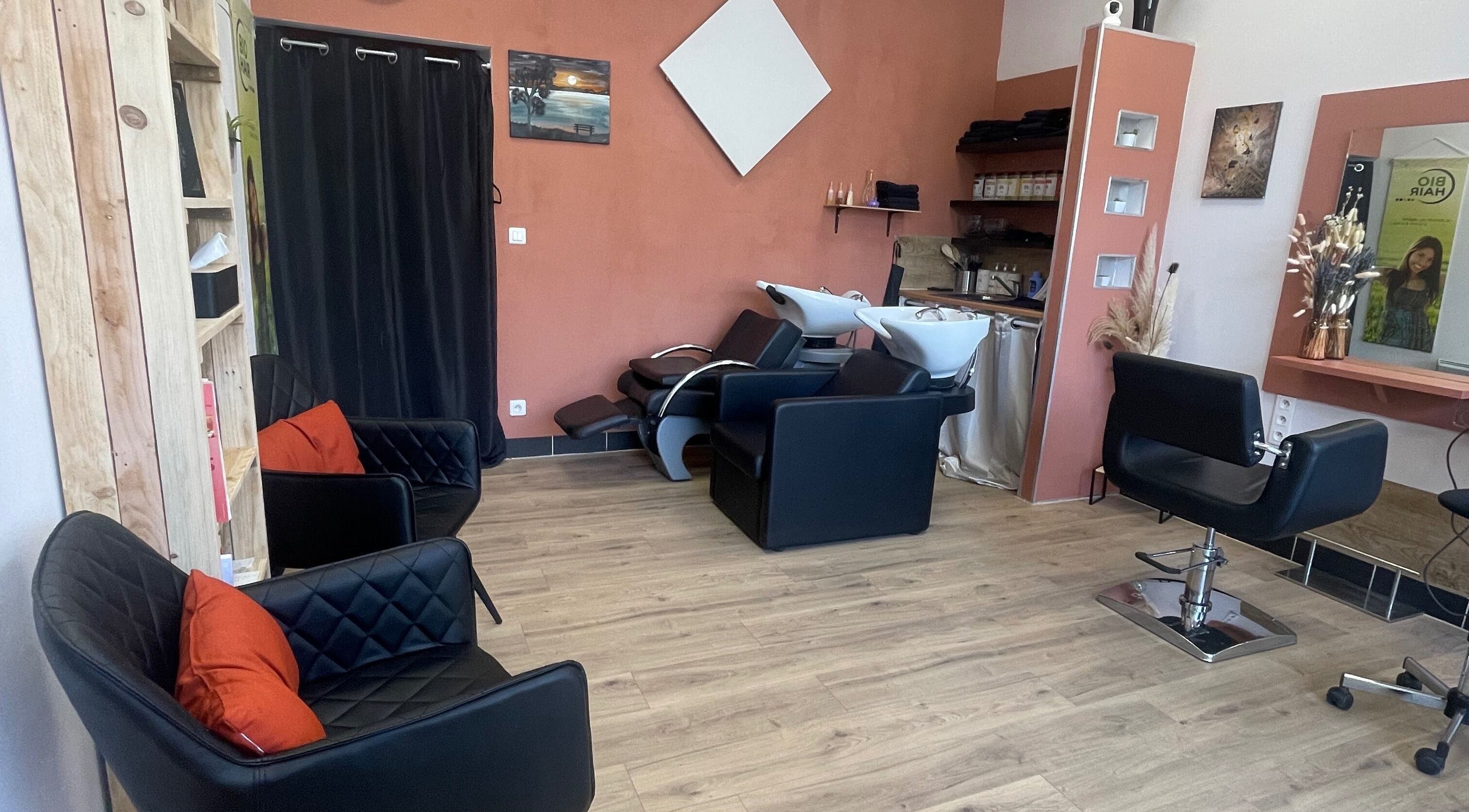 Intérieur élégant de Coiffure By Cha à Uzer, Auvergne-rhône-alpes, FR, avec fauteuils noirs.