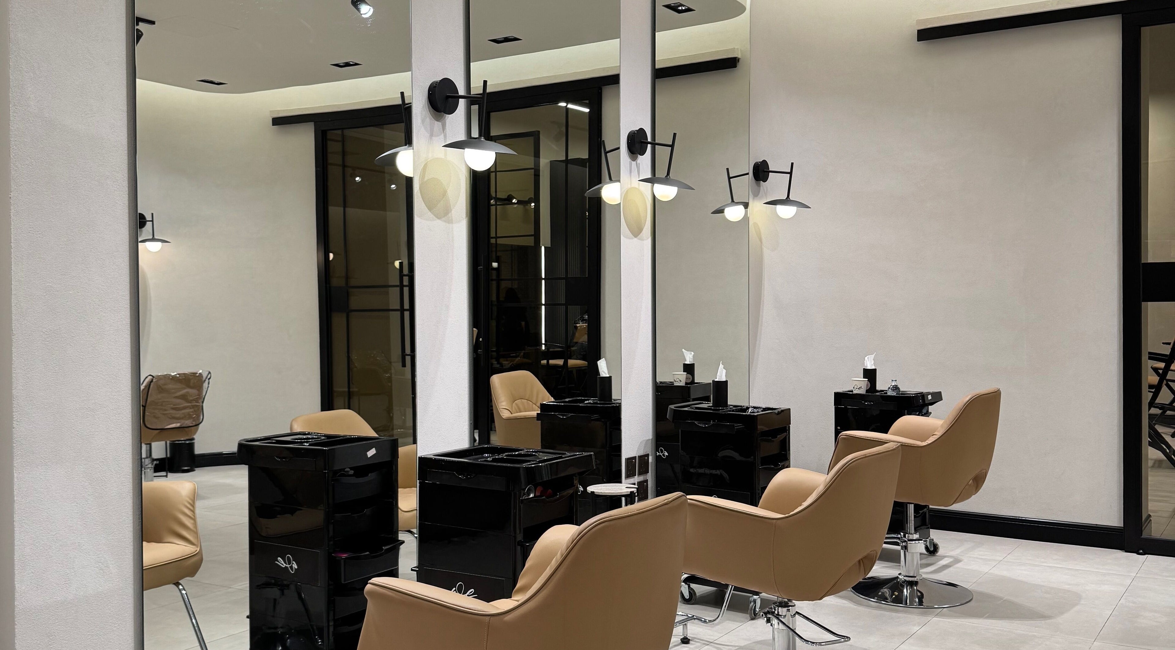 Modern salon interior at We Salon, Riyadh, Riyadh Province, SA with stylish beige chairs and sleek mirrors.