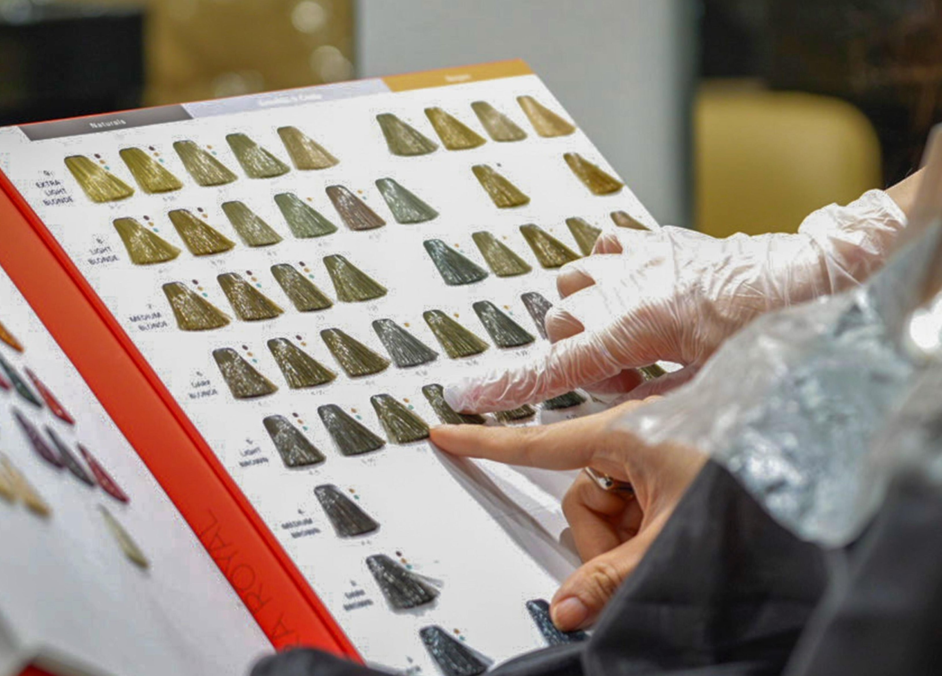 Hair color selection book at We Salon, Riyadh, Riyadh Province, SA. Finger points to shade options.