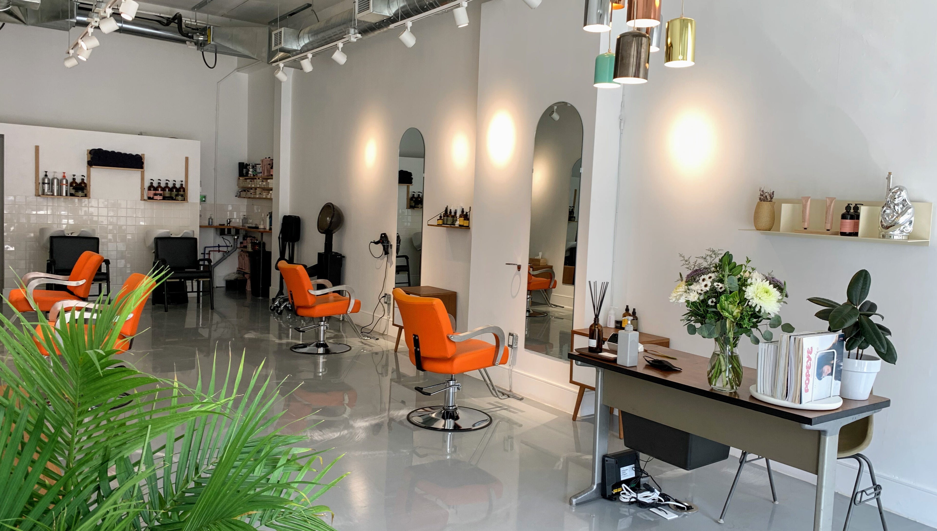 Modern salon interior at Antidote Studio, Toronto, Ontario, CA, featuring stylish orange chairs and sleek decor.