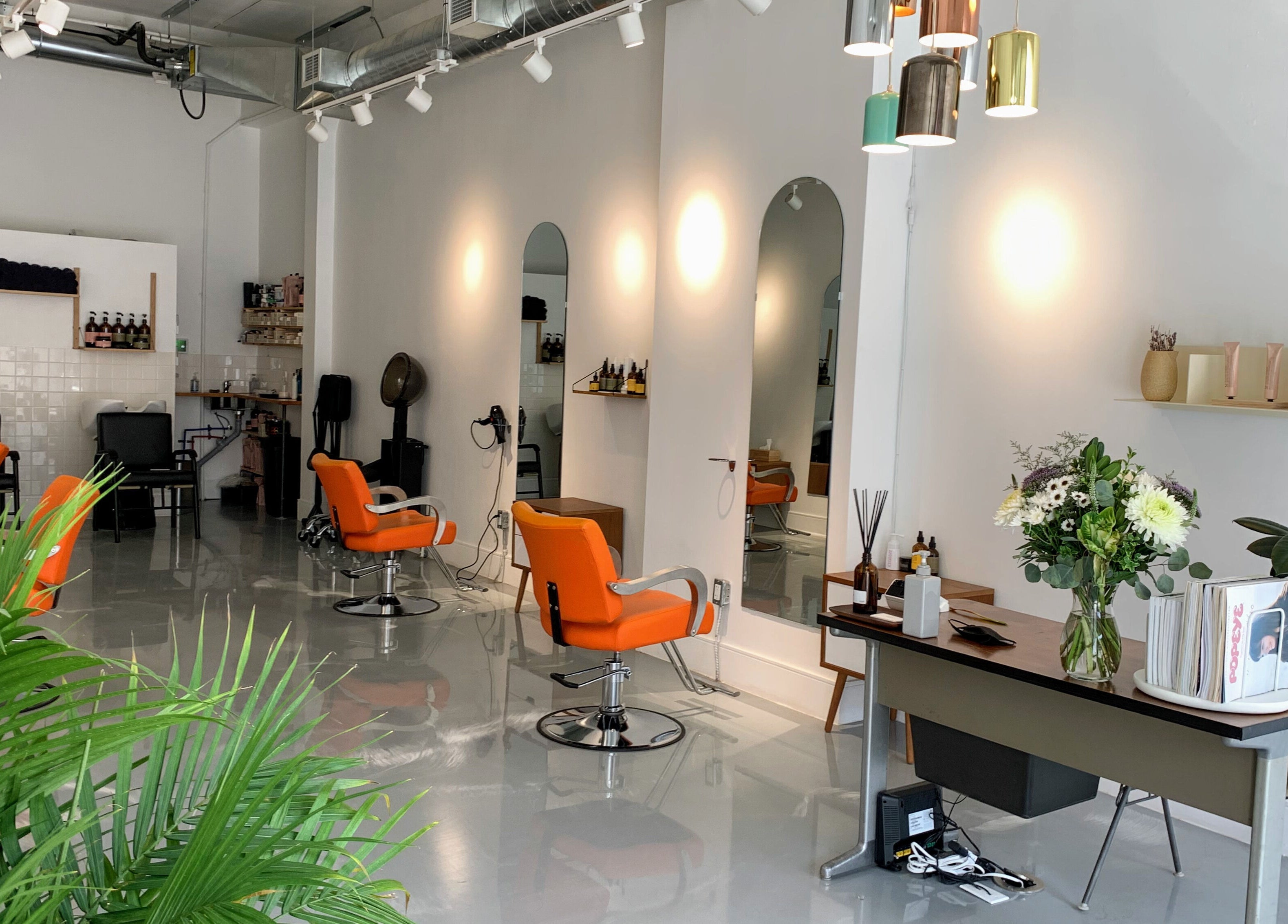 Modern salon interior at Antidote Studio, Toronto, Ontario, CA, featuring stylish orange chairs and sleek decor.